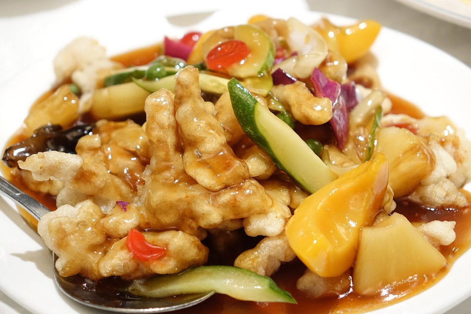 Plate of tangsuyuk with glossy sweet and sour sauce and vegetables